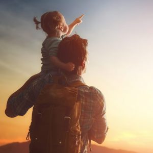 Vater und Tochter schauen Richtung Sonne, Quelle unendlicher sauberer Energie für die Zukunft.