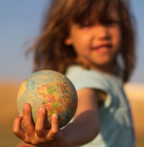 Kind hält eine kleine Kugel der Erde, Symbol für unsere Verantwortung der nächsten Generation einen sauberen Planeten zu überlassen.